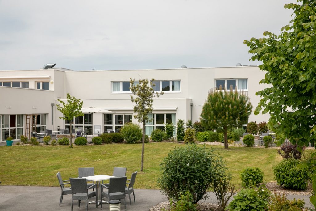 Jardin protégé avec terrasse aménagée avec tables et espace vert